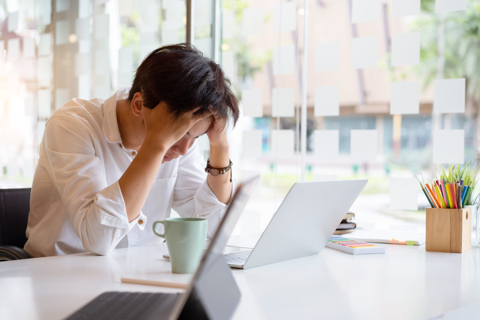 Tired frustrated young asian businessman feeling stressed holding head with hands, business problem failure concept