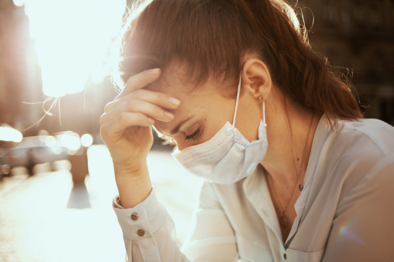 Life during covid-19 pandemic. Portrait of stressed stylish woman in blue blouse with medical mask outdoors on the city street. stressed stylish woman with mask outdoors on city street