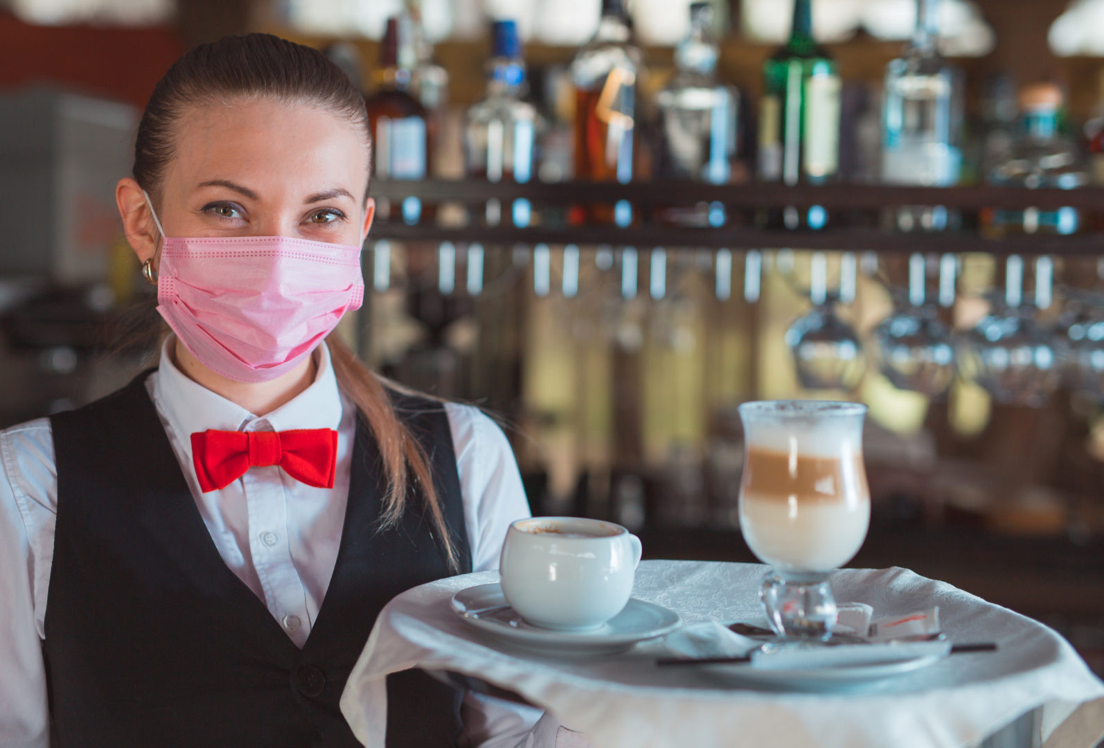 the waiter works in a restaurant in a medical mask.