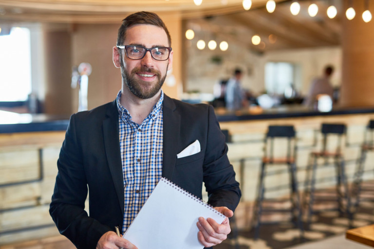 Businessman with notepad looking at camera in restaurant Catering business