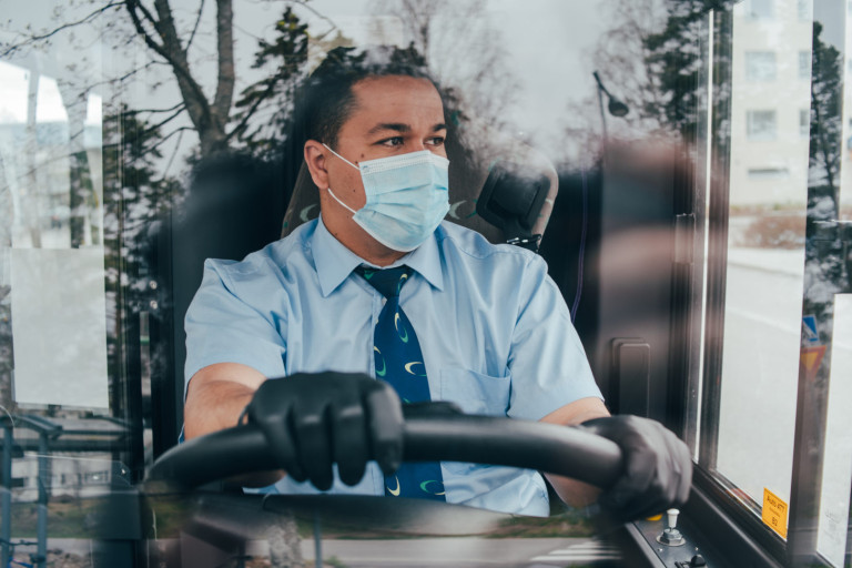 young hispanic man bus driver in a protective mask and black gloves. prevent the spread of coronavirus. young hispanic bus driver wearing a protective mask and looks at road. quarantine. covid 19. prevent the spread of coronavirus. young hispanic bus driver wearing a protective mask and looks at road.