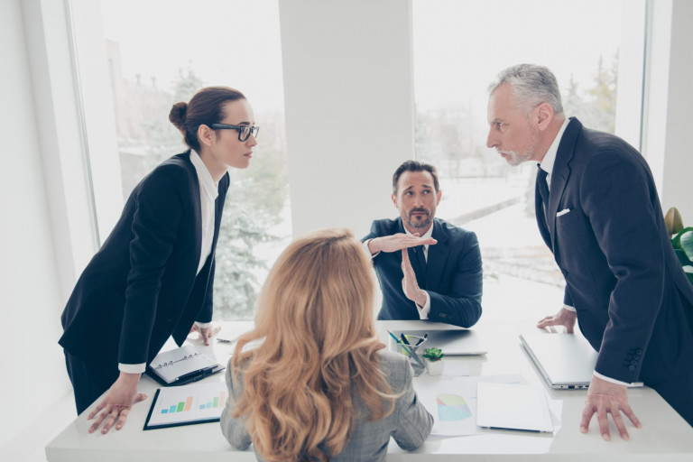 Two stylish business persons in suits having disagreement, war, conflict, standing near desktop in front of each other, face to face with disrespect expression, partner showing stop sign with hands Two stylish business persons in suits having disagreement, war, conflict, standing near desktop in front of each other, face to face with disrespect expression, partner showing stop sign with hands