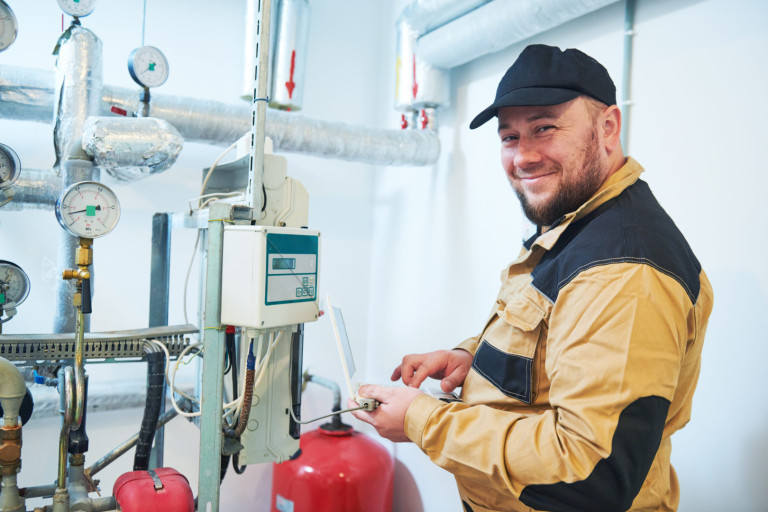 heating equipment inspecting. engineer or plumber inspector in boiler room taking readouts or adjusting heat meter heating engineer or plumber inspector in boiler room taking readouts or adjusting meter
